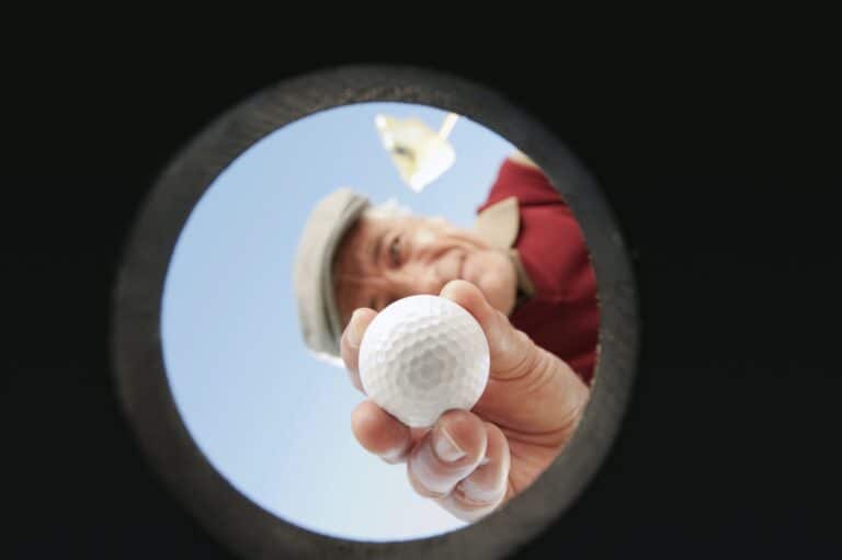 Italy, Kastelruth, Mature man holding golf ball into hole