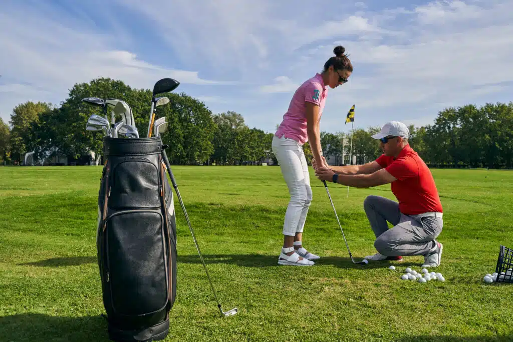 Golfanfängerin übt mit ihrem Golftrainer den richtigen Golfgriff mit dem perfekten Griffdruck